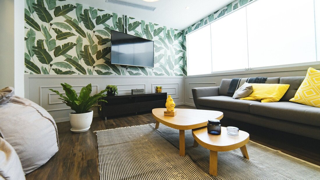 Picture of a modern apartment living room with green and white designer floral wallpaper on the feature tv wall. 