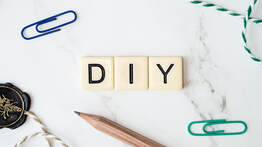 Picture of a pencil, green and blue paperclips and three scrabble letters that spell DIY 