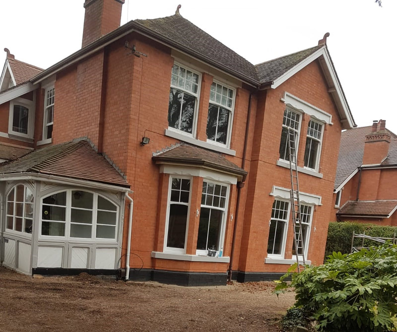 A picture of a detached property with the exterior newly painted white and grey on all wood work and stone masonary by Painting and Decorating Nottingham