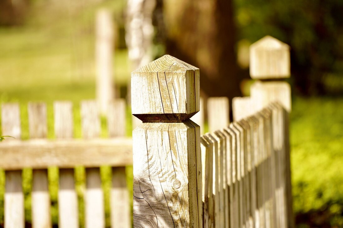 Picture of a timber fence post and fence stretching into the distance that requires painting